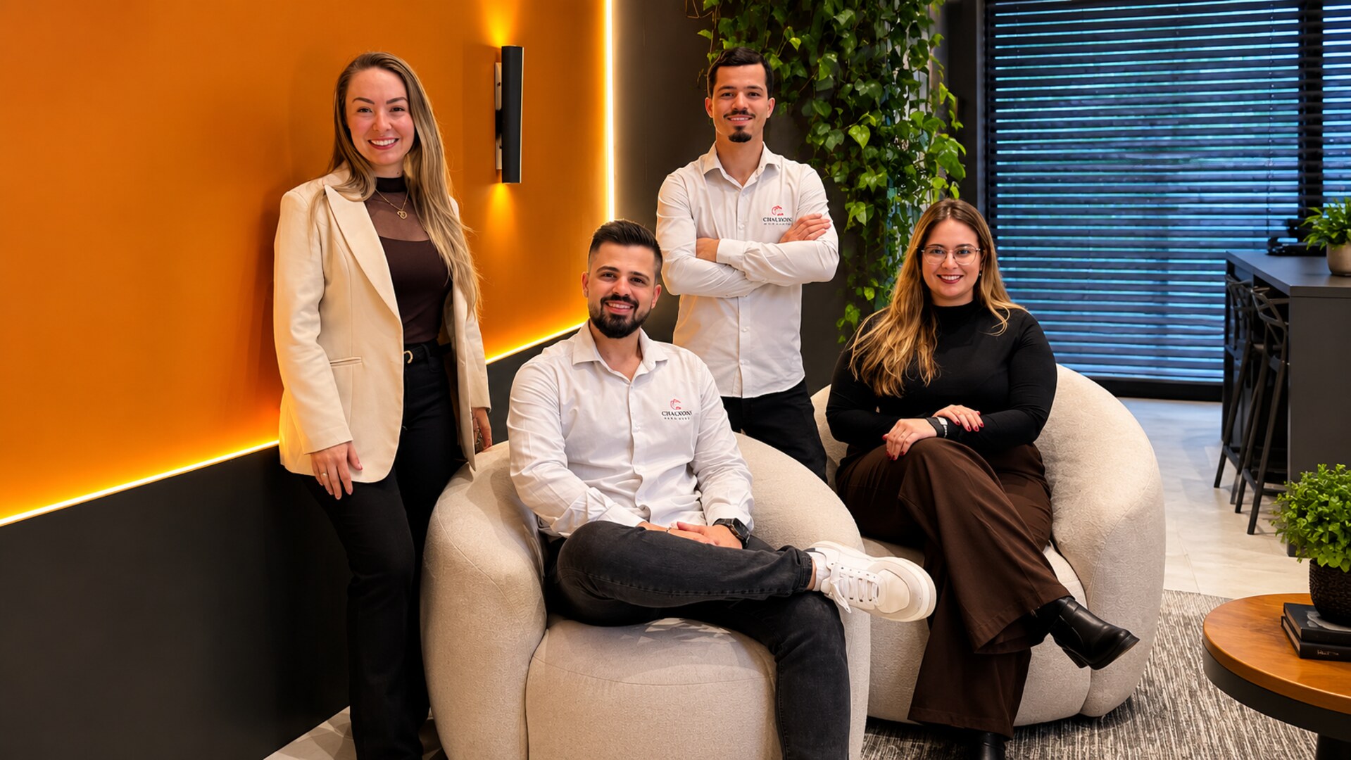 Equipe da Casa Canova Planejados em ambiente corporativo com parede de plantas e iluminação indireta